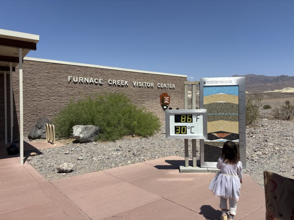 Outdoor thermometer display in front of Furnace Creek Visitor Center, showing extreme heat