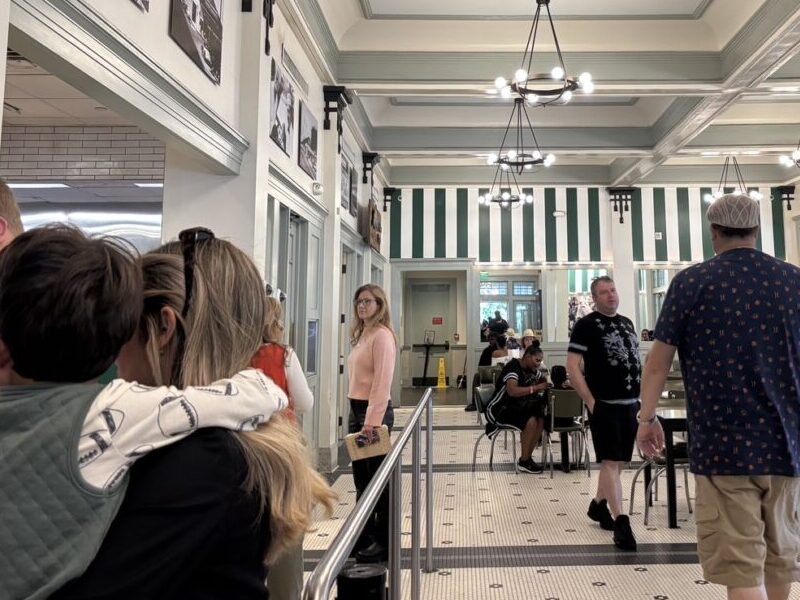Café Du Monde の店内で、順番待ちの人々とレトロなインテリアが並ぶ風景。