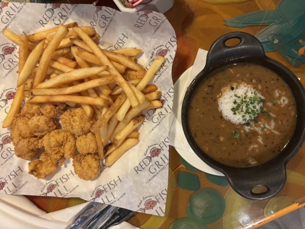 Red Fish Grill のテーブルに並べられたフライドシュリンプとポテト、ガンボのセット。