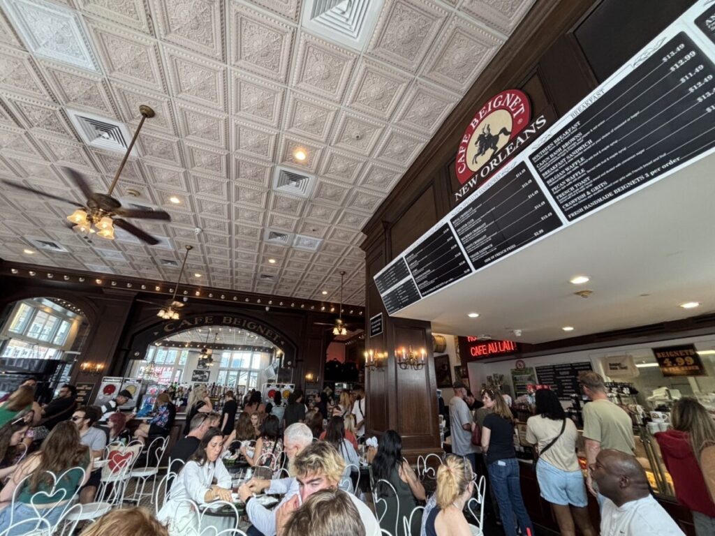 カフェ・ベニエの店内で、多くの人が朝食やベニエを楽しんでいる様子。