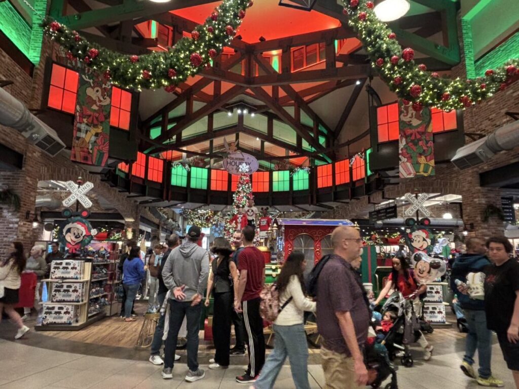 クリスマスシーズンのワールド・オブ・ディズニー店内。ガーランドや赤と緑の照明で装飾され、多くの来場者で賑わっている様子。