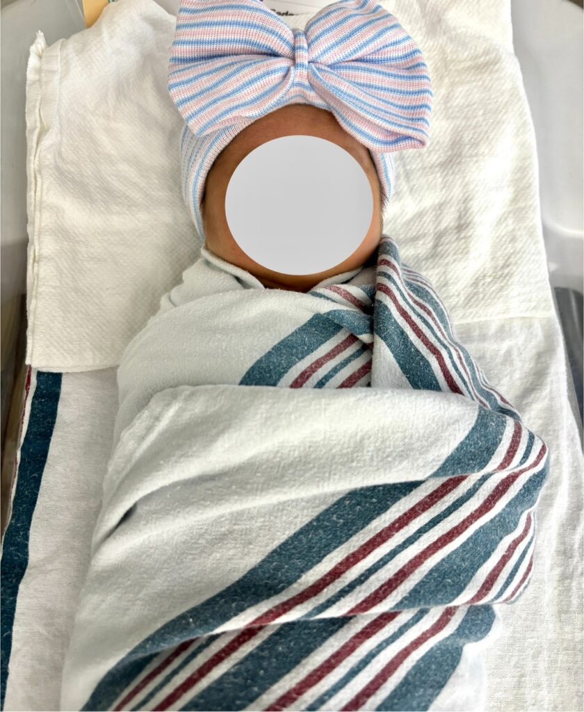 病院のおくるみと帽子に包まれてベッドで寝ている新生児